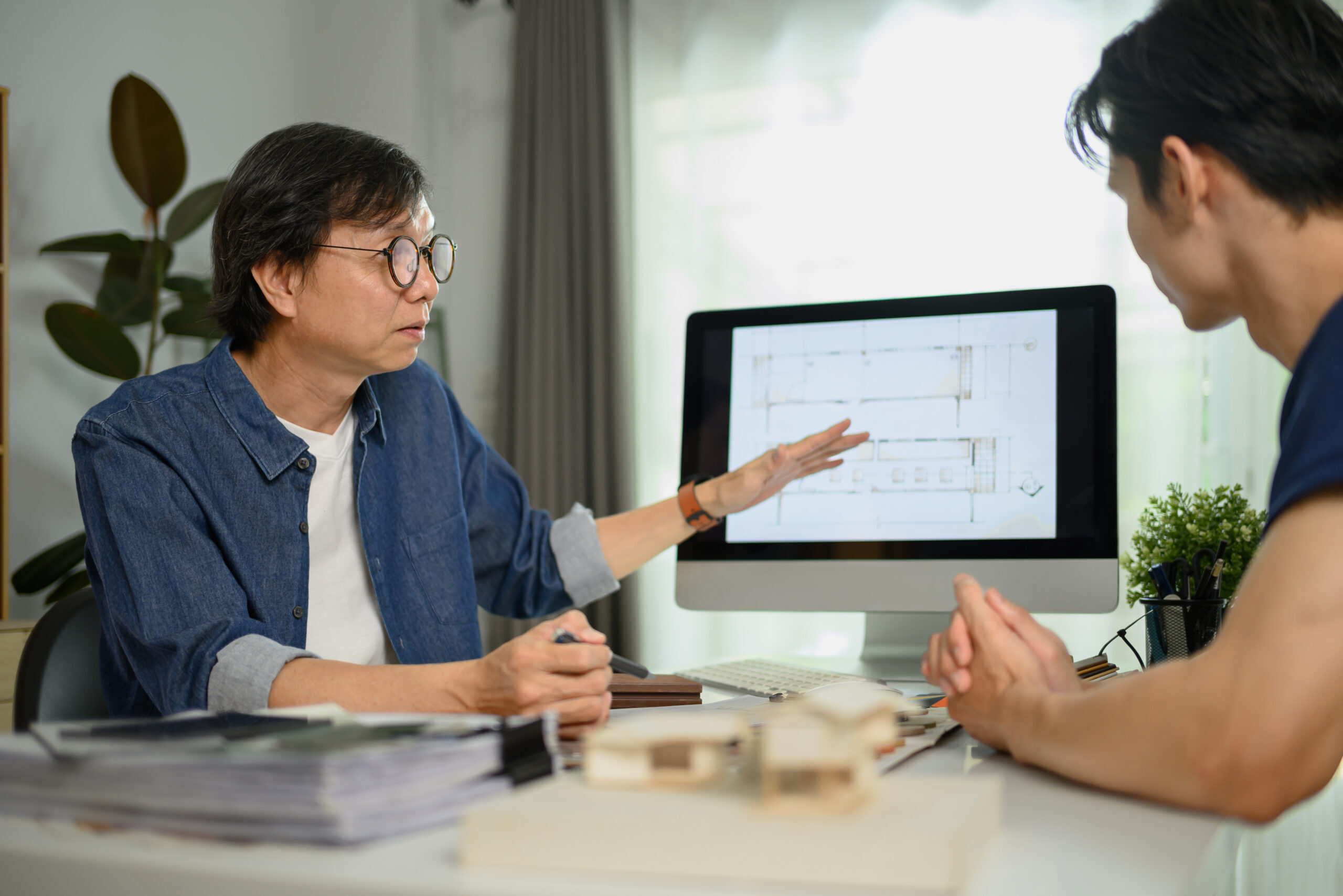 Professional interior designer sharing ideas and showing architectural plan to male client